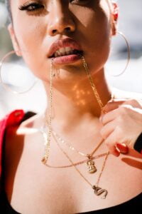woman biting gold-colored necklace av globale&#8217;s role in boosting thailand&#8217;s sustainable growth in the gemstones and jewelry industry